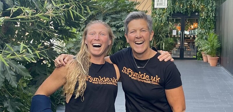 Sarah Thornely standing with April Zilg, arms around each other, looking happy, and both wearing SUPjunkie.uk t-shirts