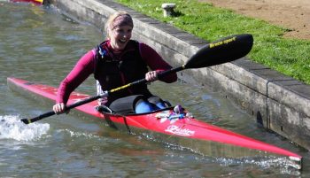 DW race fanatic Kat Wilson arrives at a portage, smiling in her skinny kayak